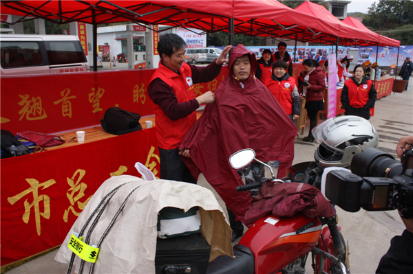 梧州市總工會的黨員義工們在市東出口春運服務站助力“摩托大軍”平安返鄉(xiāng)，幫助他們檢查車輛和行李，穿上雨衣。--黃賀峰攝.j